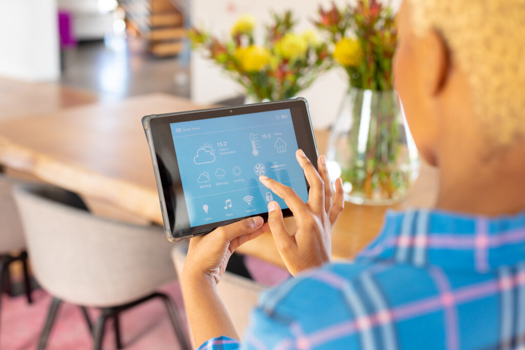 African american woman using tablet with smart home interface. Technology, home alone, domestic life and lifestyle concept.