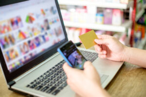 Hand holding credit card and using laptop with smartphone for paying shopping online showing the mobile marketing in E-Commerce
