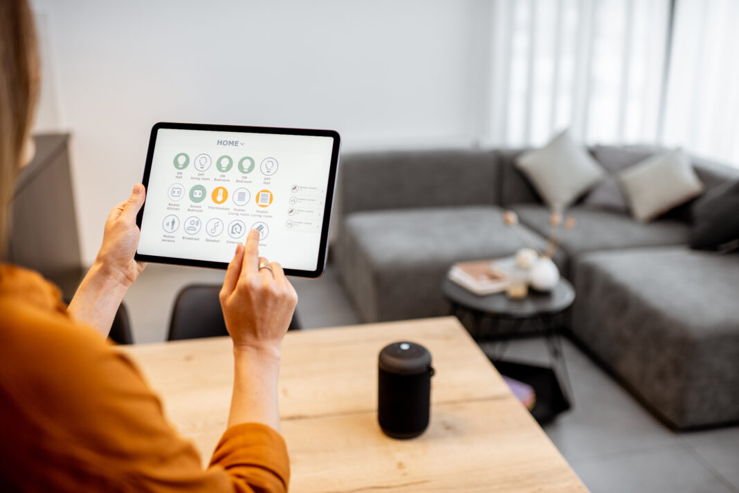 Young woman controlling home with a digital touch screen panel. Concept of a smart home and mobile application for managing smart devices at home